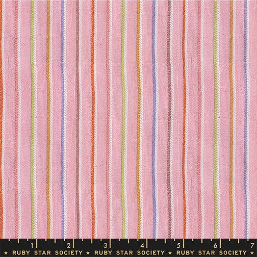 Fabric with multicolored vertical stripes on a pink background, featuring the Ruby Star Society label. Collection of colorful fabric swatches with various patterns on a white background Warp & Weft Mystic Fable Yarn Dyed Woven Fabrics by Alexia Marcelle Abegg for Ruby Star Society for Moda Fabrics