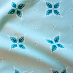 Close-up of fabric with blue and white floral pattern on a light blue background in a bandana style with hidden wishbone motif
