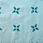 Close-up of fabric with blue and white floral pattern on a light blue background in a bandana style with hidden wishbone motif