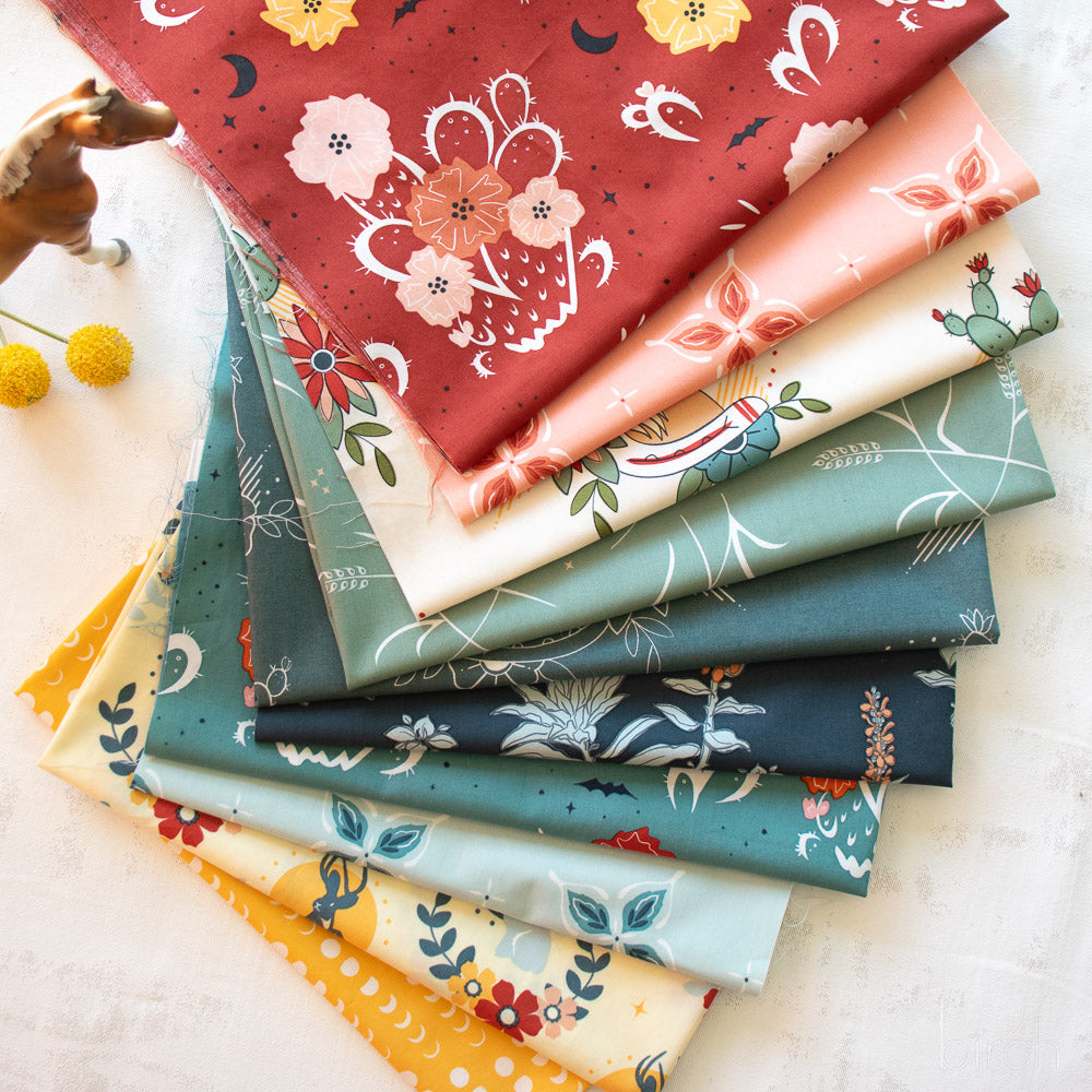 Stack of colorful fabric swatches with various patterns on a light surface.